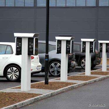 E-Autos laden an Ladesäulen auf einem Firmenparkplatz. E-Autos laden an Ladesäulen auf einem Firmenparkplatz.