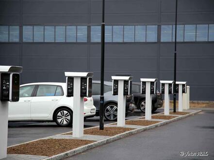 E-Autos laden an Ladesäulen auf einem Firmenparkplatz.
